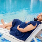 An expectant mother relaxing by the poolside during an outdoor maternity photography session in a premium gated community on Sarjapur Road, Bangalore.